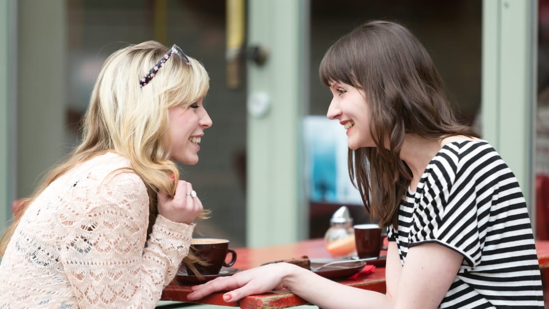 dua wanita sedang mengobrol di cafe